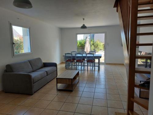 een woonkamer met een bank, een tafel en stoelen bij Maison 400m de la mer in Pénestin