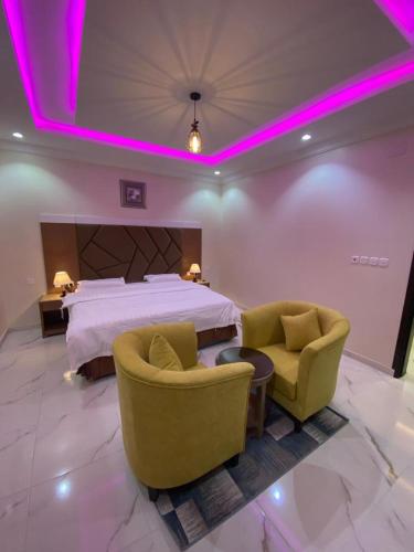 a hotel room with a bed and two chairs at فرويال للشقق المخدومة in Nughaylah