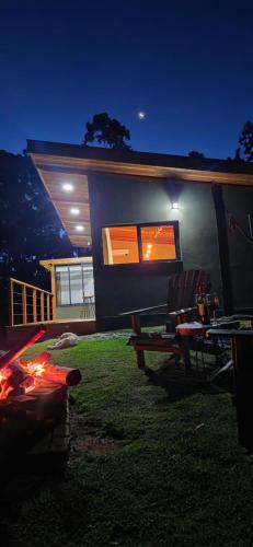 a house with a table and chairs in front of it at Chalé Manacá in Sapucaí-Mirim
