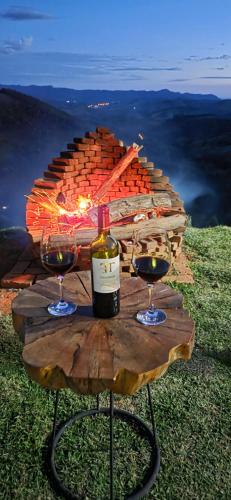 a table with two glasses and a bottle of wine at Chalé Manacá in Sapucaí-Mirim