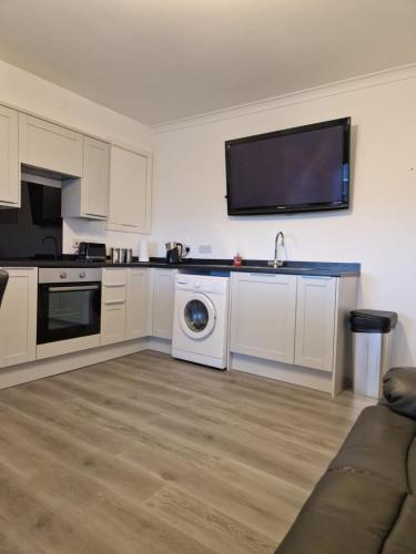 una cucina con lavatrice e una TV a parete di Rook View, Modern Coastal Retreat with Free Parking a Buckie