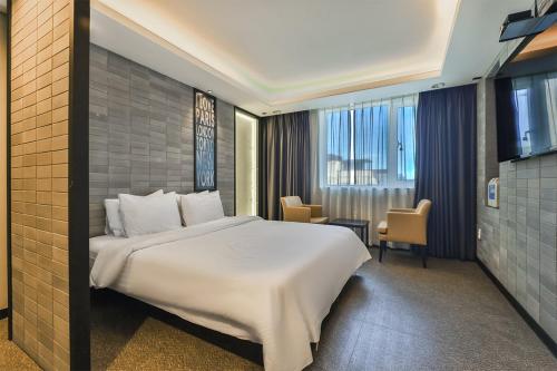 een slaapkamer met een groot wit bed in een kamer bij Moonbay Hotel in Busan