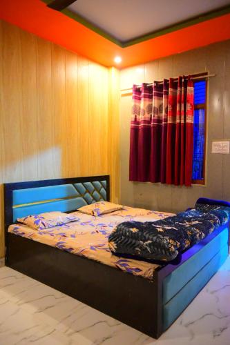 a bedroom with a bed with a blue frame and colorful curtains at Mahakal homestay in Ayodhya