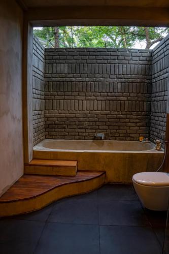 a bathroom with a tub with a window and a toilet at VeeRaa Retreat in Habarana