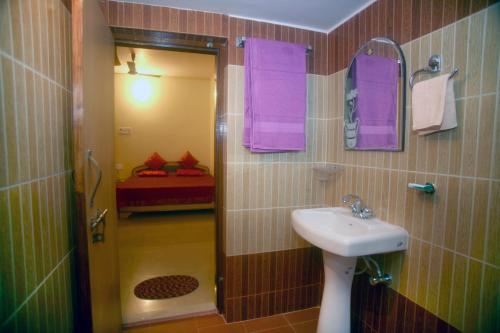 a bathroom with a sink and a shower with purple towels at Sheetal Homestay in Varanasi