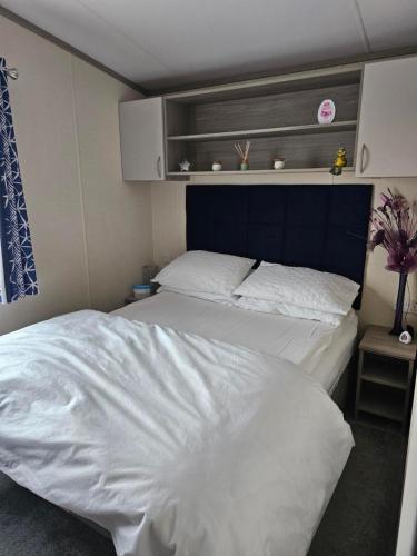 a bedroom with a large white bed with a blue headboard at 205 Holiday Resort Unity 6 berth No Pets Passes Optional in Brean
