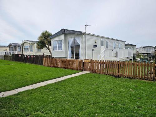 a house behind a wooden fence with a yard at 205 Holiday Resort Unity 6 berth No Pets Passes Optional in Brean