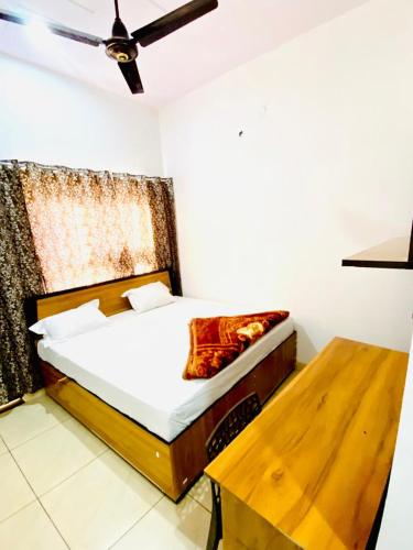 a bedroom with a bed and a wooden table at Dh Hotel in Bhiwāni