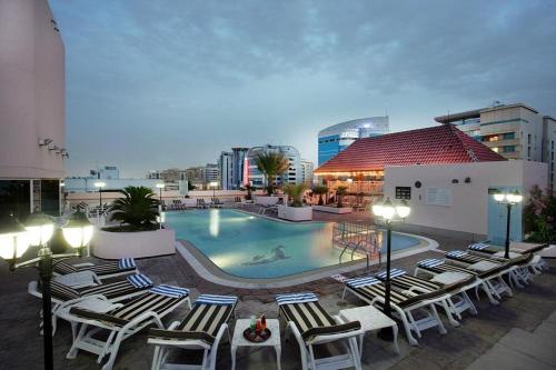 a swimming pool with lounge chairs and a building at Knight Castle Hotel - Formerly known as Carlton Palace Hotel in Dubai