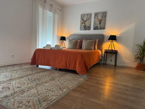 a bedroom with a bed with an orange blanket and a rug at DDM Studio - O paraíso do Sítio da Nazaré in Nazaré