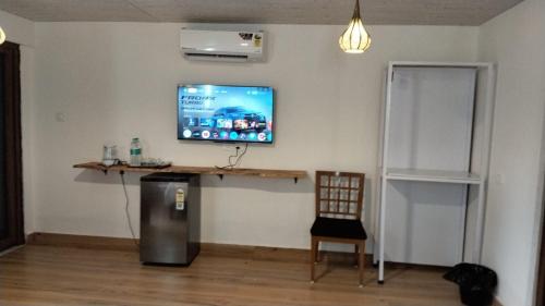 a television on a wall with a table and a chair at Sea Shades Palolem Resort in Palolem