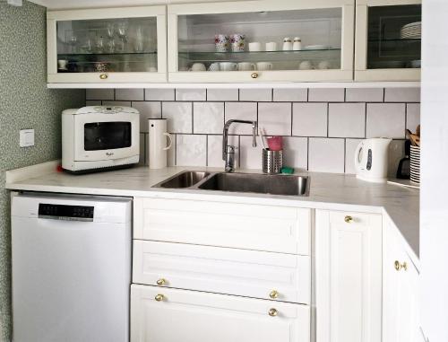 een witte keuken met een spoelbak en een magnetron bij Unikt sommarboende in Färjestaden