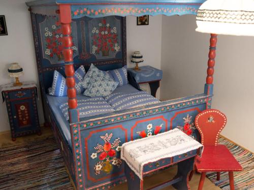 a bedroom with a blue bed and a red chair at Schwaigerhof in Wackersberg