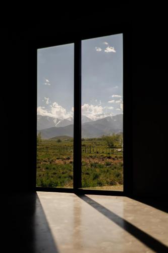 a window with a view of a field and mountains at Om infinity - Soft opening in Tupungato