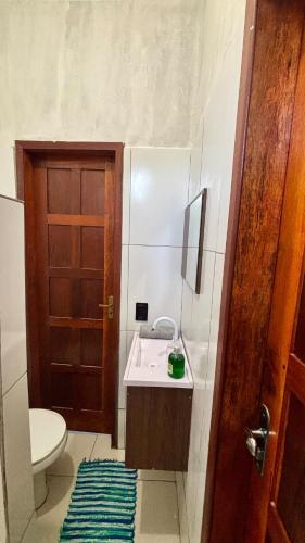 a bathroom with a sink and a toilet and a door at Taboca Chalé na Rua do Serrão in Cairu