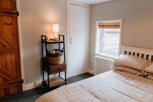 a bedroom with a bed and a lamp and a window at River Cottage in Beccles