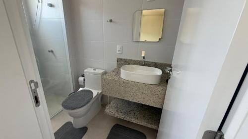 a bathroom with a toilet and a sink and a mirror at Cód 2 - Cobertura de 2 dormitórios na Praia Grande in Rodeio