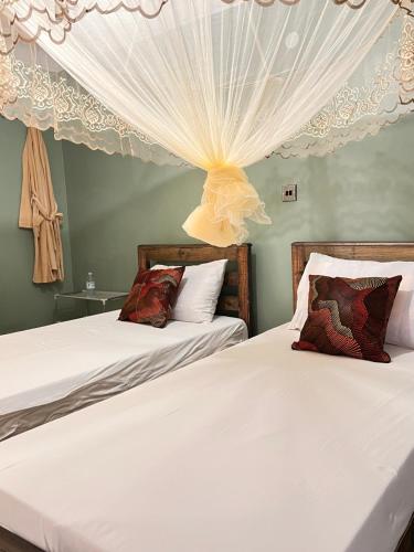 KisoroMufasha Boutique Suites的卧室设有两张床,配有白色窗帘