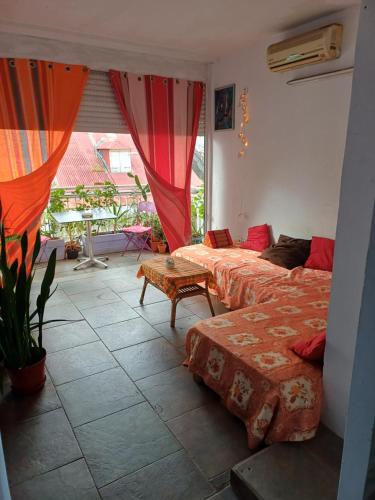 een kamer met twee bedden, een tafel en een raam bij Chez Brahim in Pointe-à-Pitre