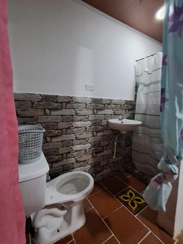 een badkamer met een toilet en een bakstenen muur bij Faera Hostel in Darién