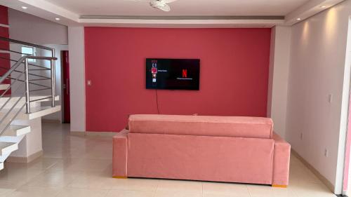 a red wall with a couch in a living room at Family Space - Chacara Rosa Beautiful and Comfortable in Cuiabá