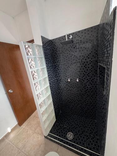 un bagno con doccia con piastrelle nere di Departamento Moderno y Centrico check in autonomo no necesitas llaves a Guaymas