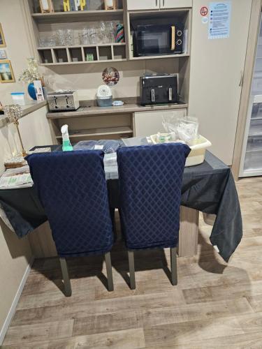 a table in a kitchen with two blue chairs at 205 Holiday Resort Unity 6 berth No Pets Passes Optional in Brean