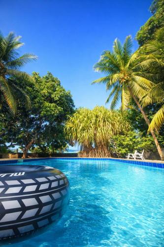 een zwembad met palmbomen op de achtergrond bij Maison Tropical in Paracuru
