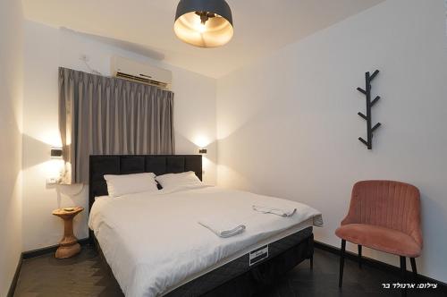 a bedroom with a bed and a red chair at Don Leon Boutique in Even Menahem
