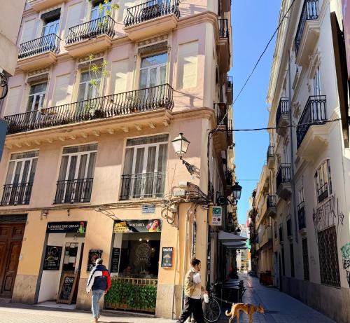 twee mensen lopen door een straat voor een gebouw bij Teixidors de Palomar - PalomarGroup in Valencia