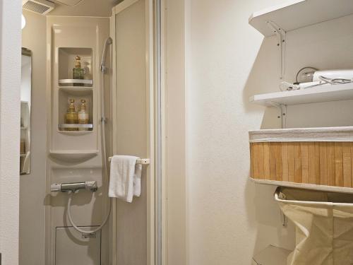 a bathroom with a shower with bottles on the door at Hermitage Hotel Nishishin in Tokyo