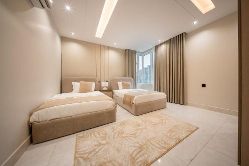 a bedroom with two beds and a large window at Revana for families in Jeddah