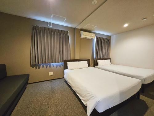 a hotel room with two beds and a couch at Hermitage Hotel Nishishin in Tokyo