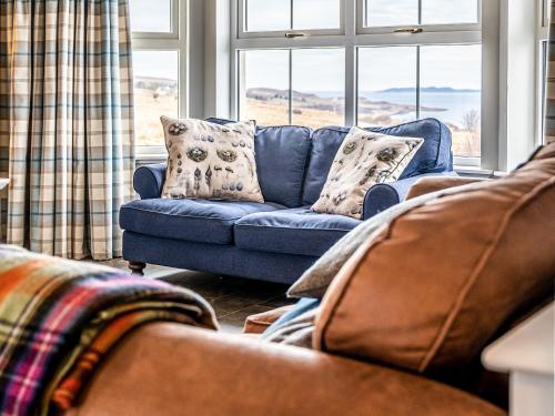 un canapé bleu assis dans un salon avec une fenêtre dans l'établissement Kildonan, à Durnamuck