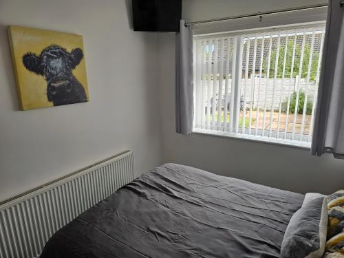 a bedroom with a bed and a picture of a cow at 58 Clifton Rise in Abergele
