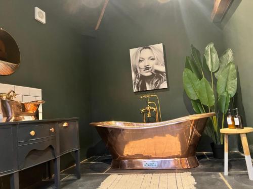 ein Badezimmer mit einer Kupferbadewanne und einem Bild einer Frau in der Unterkunft Coach Lodge in Torworth