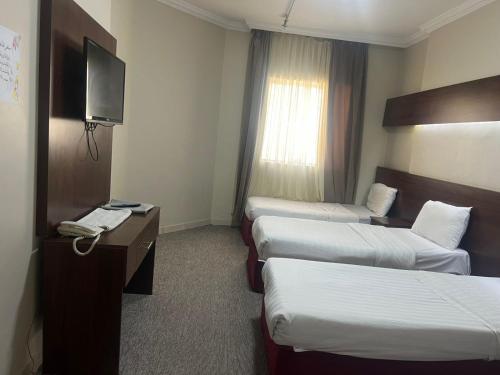 a hotel room with two beds and a television at فندق منارة العزيزية in Al Gharīth