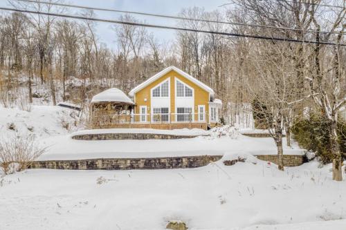 ein gelbes Haus mit einem Teich im Schnee in der Unterkunft Spa Lake - Naturo lac Sept-Iles in Saint-Raymond