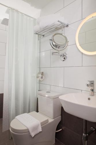 a white bathroom with a toilet and a sink at Gold3 Boutique Hotel in Kuala Lumpur