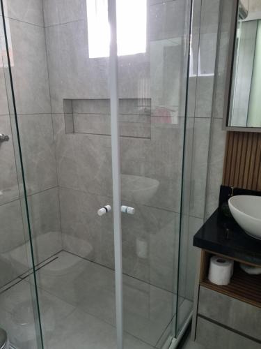 a shower with a glass door next to a sink at Lugar Acolhedor e Próximo a Natureza in Florianópolis