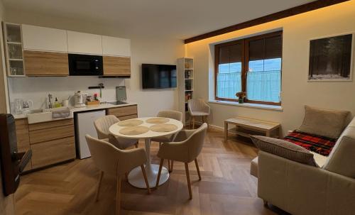 a kitchen and a living room with a table and chairs at Kwietny Stoczek 70 in Białowieża