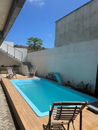 a large swimming pool with two chairs next to a building at Pousada Bella Flor in Baía Formosa