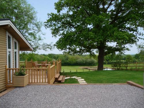 een huis met een terras en een tuin met een boom bij Wattles-E4527 in Uplowman