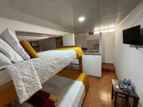 een slaapkamer met 2 bedden en een kleine keuken bij Ayenda Marana in Manizales