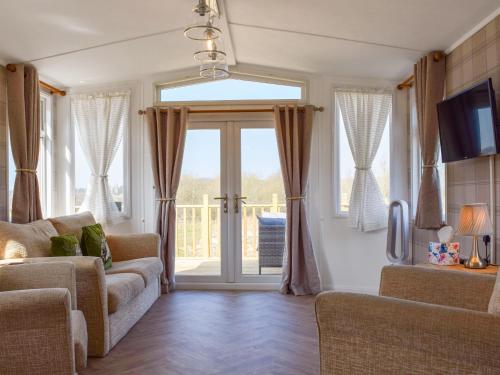 ein Wohnzimmer mit Sofa und Glasschiebetür in der Unterkunft Owl Lodge - Uk49144 in Hartshorne