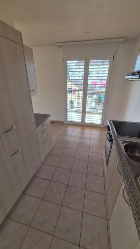 une cuisine avec des armoires blanches et un sol carrelé dans l'établissement Sunny Place Geneva 15 min Train, à Versoix