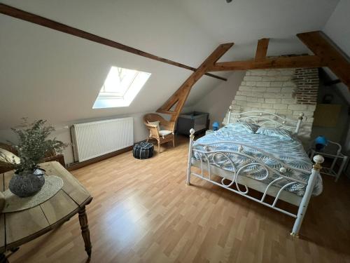 une chambre avec un lit et une chaise dans un grenier dans l'établissement Gîte Baie de Somme à 5 mn de la mer Chez Nath & Jack, à Woignarue
