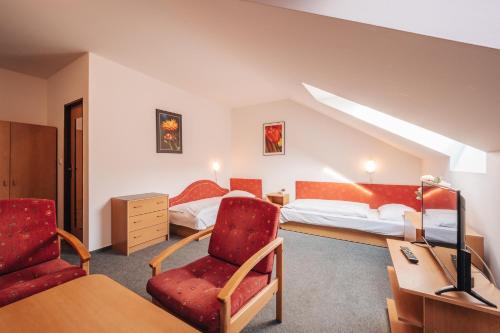 een hotelkamer met twee bedden en een stoel bij Penzion U Pošty Blatná in Strakonice