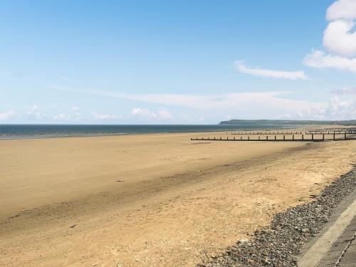 a sandy beach with a pier in the distance at Long John Cottage in Redcar