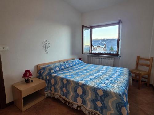 a bedroom with a bed and a window and a chair at Casa Giardina-bilocale con deposito biciclette-sci in San Giacomo